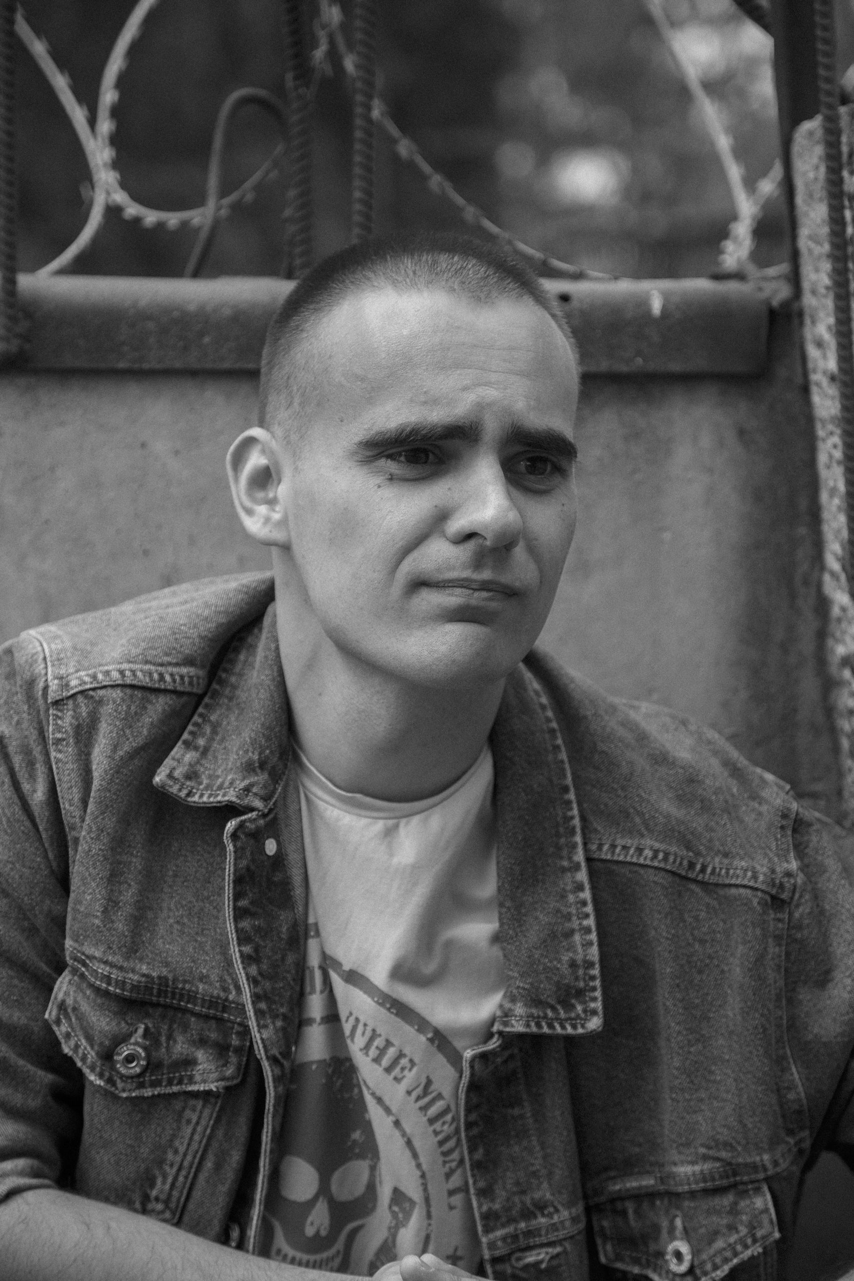 Black and white portrait of a man in a denim jacket outdoors.