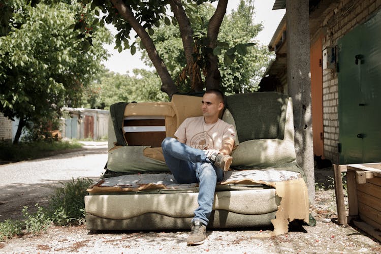 Man Sitting On A Destroyed Couch