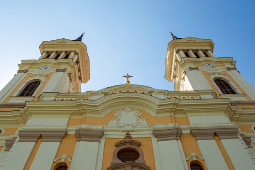 Majestic church facade under a clear blue sky, capturing historical architecture from a low angle.