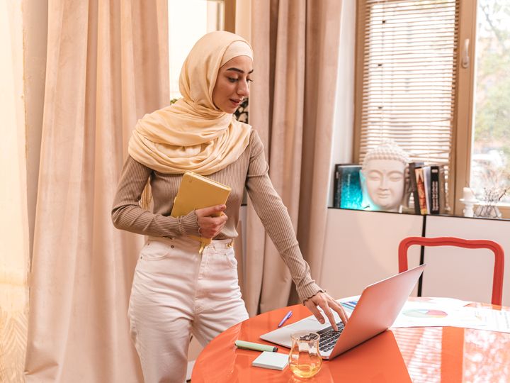 Muslim woman in hijab studying online with a laptop at home
