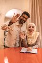 A Man and a Woman Waving Hands while Smiling at the Camera