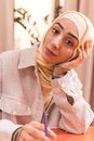 A Woman Wearing Hijab Looking at the Camera while Holding a Pen