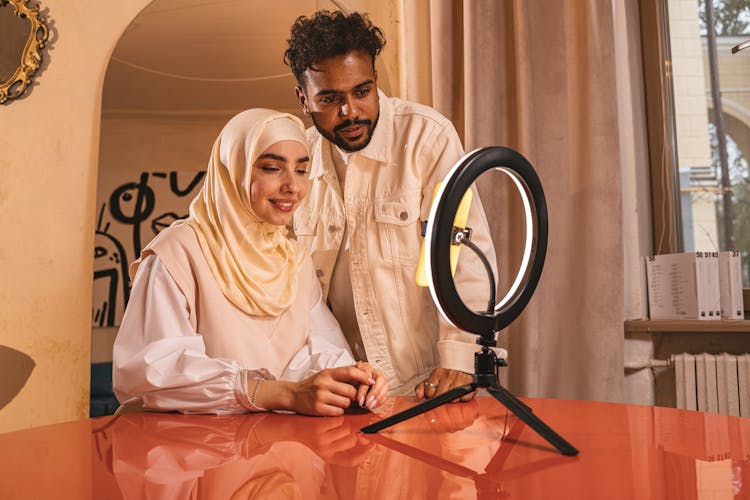 A Man And Woman Facing The Ring Light On The Table