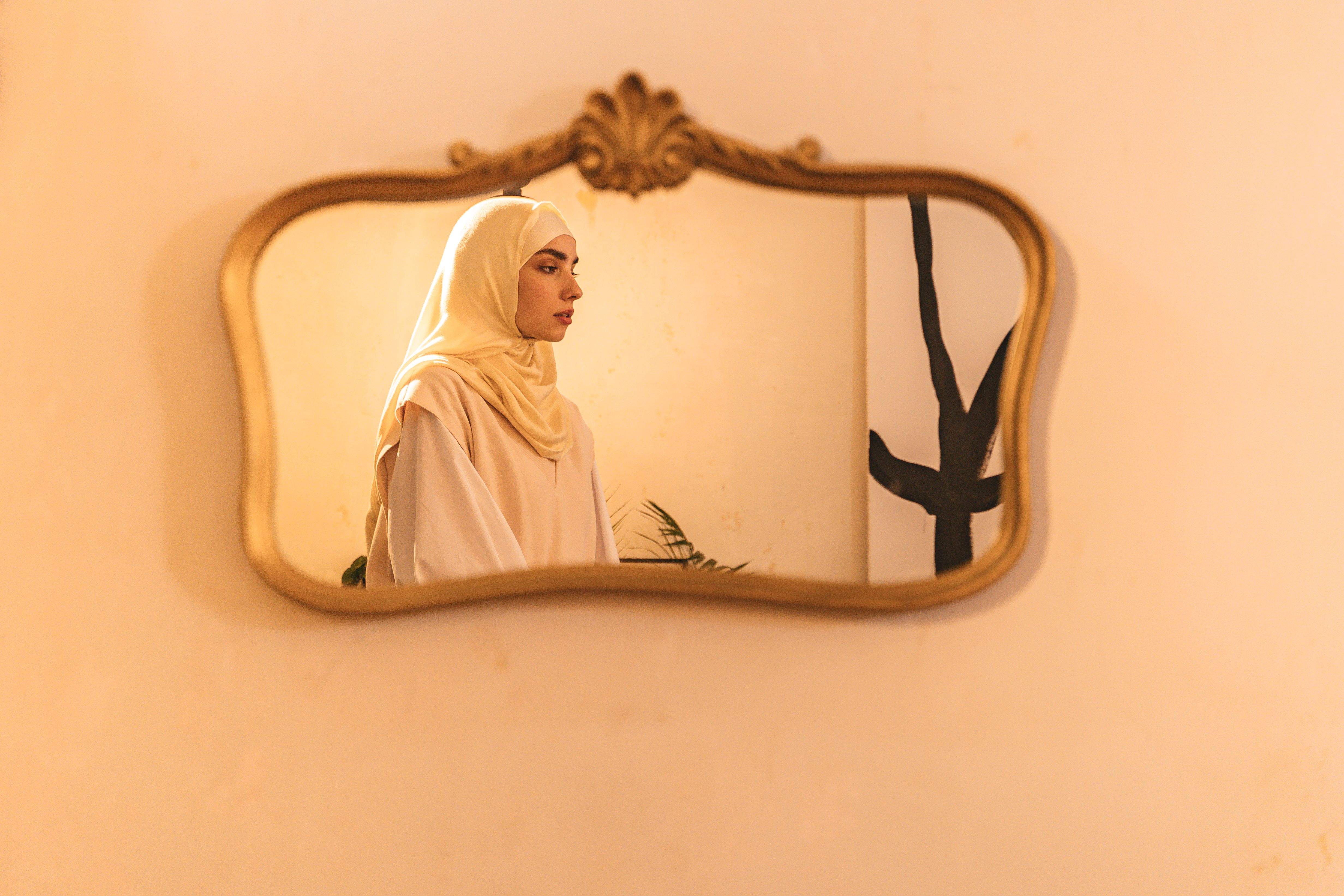 Elegant portrait of a woman in hijab reflected in a vintage mirror.