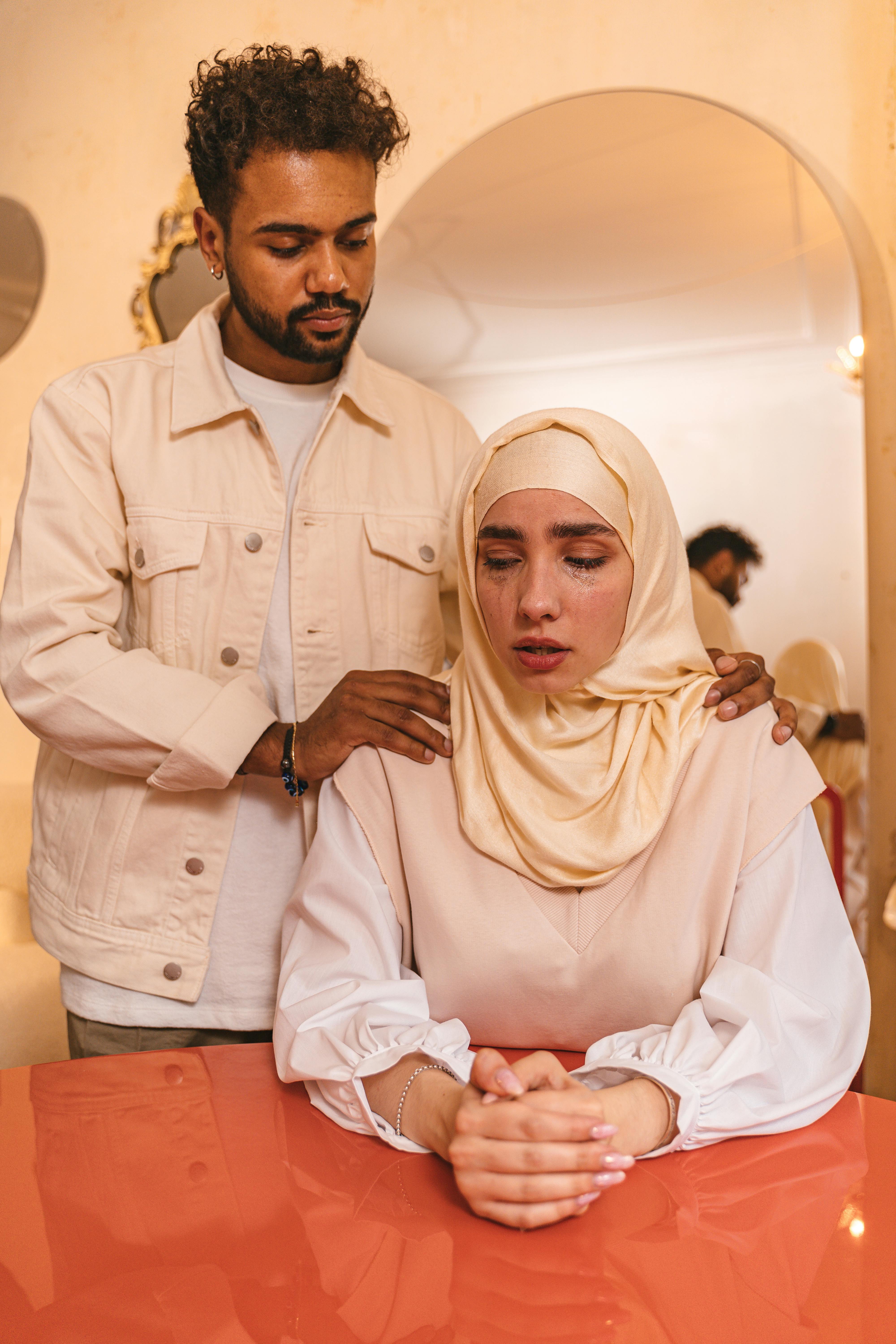 man comforting crying woman in hijab