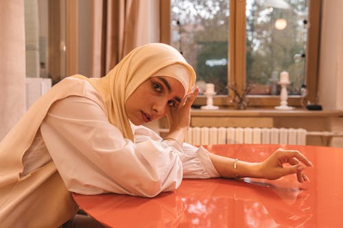 A Woman Wearing Hijab while Sitting Near the Table