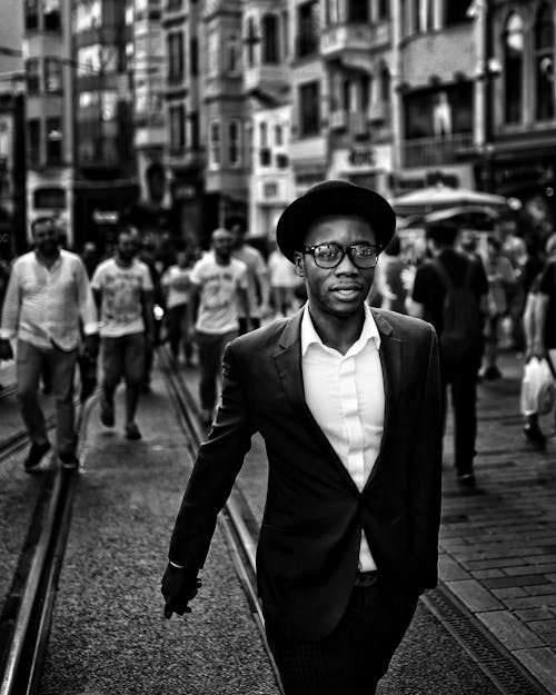 A Man in Black Suit Walking on the Street
