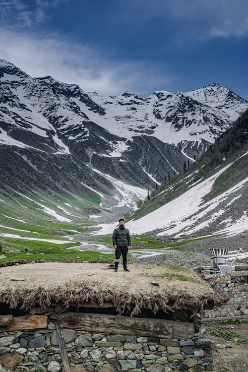 Free A Man Standing Near the Snow Covered Mountain Stock Photo