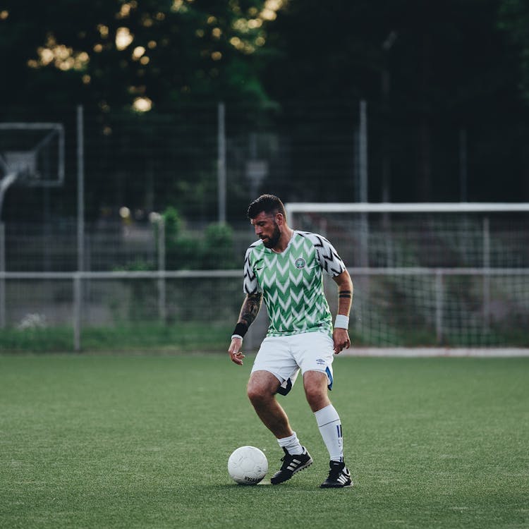 A Man In Printed Shirt And White Short Playing Soccer On The Field