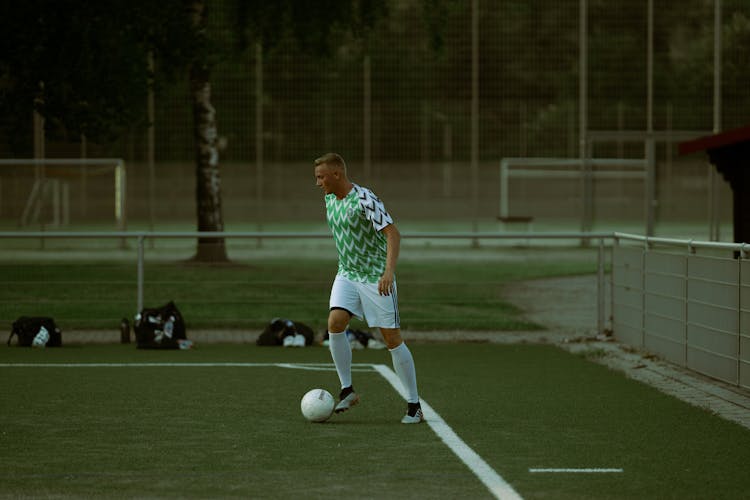 A Man In Printed Shirt Playing Soccer On The Field