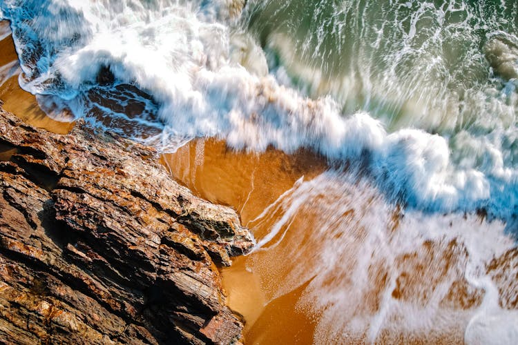 Overhead Shot Of Sea Waves Crashing Near A Rock