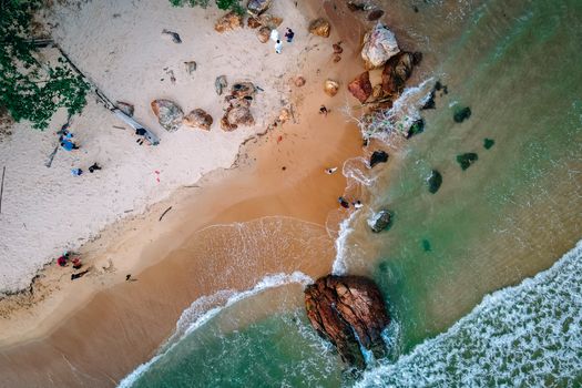 Stunning aerial shot of Chukai Beach, Terengganu with clear water, rocks, and people enjoying the shore.