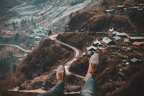 Person Wearing White Sneakers With Overlooking of Village on Hills