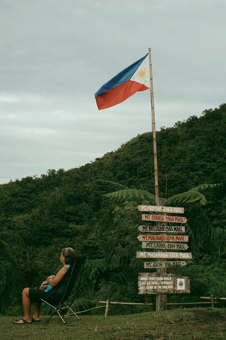 A Man Sitting Beside The Flagpole With Philippines Flag