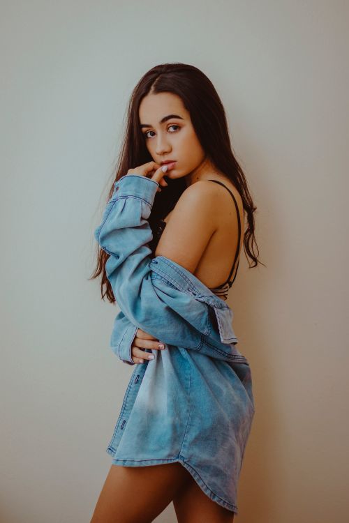 Free Elegant portrait of a young woman wearing a denim jacket in a thoughtful pose. Stock Photo