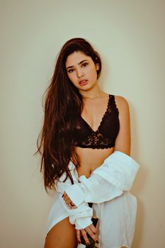 Model in black lace lingerie with long hair posing confidently indoors for fashion photoshoot.