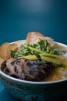 Close-up of a hearty Asian soup with fresh herbs and vegetables in a decorative bowl.