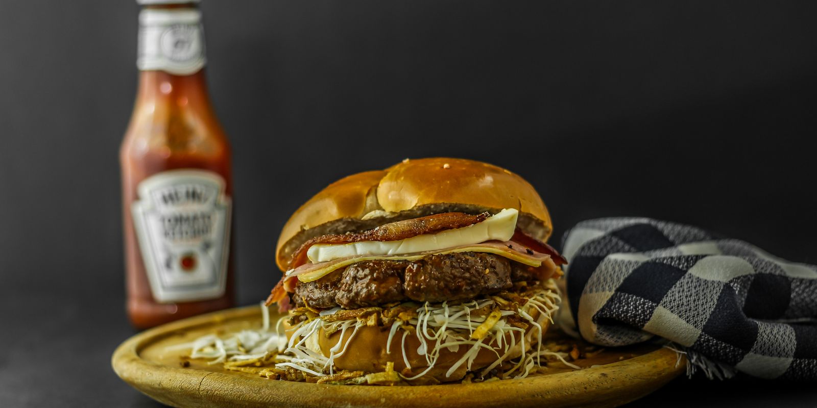 A gourmet burger with cheese served on a wooden plate
