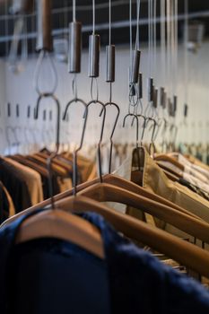 Close-up of a variety of clothes hanging on wooden hangers in a store.