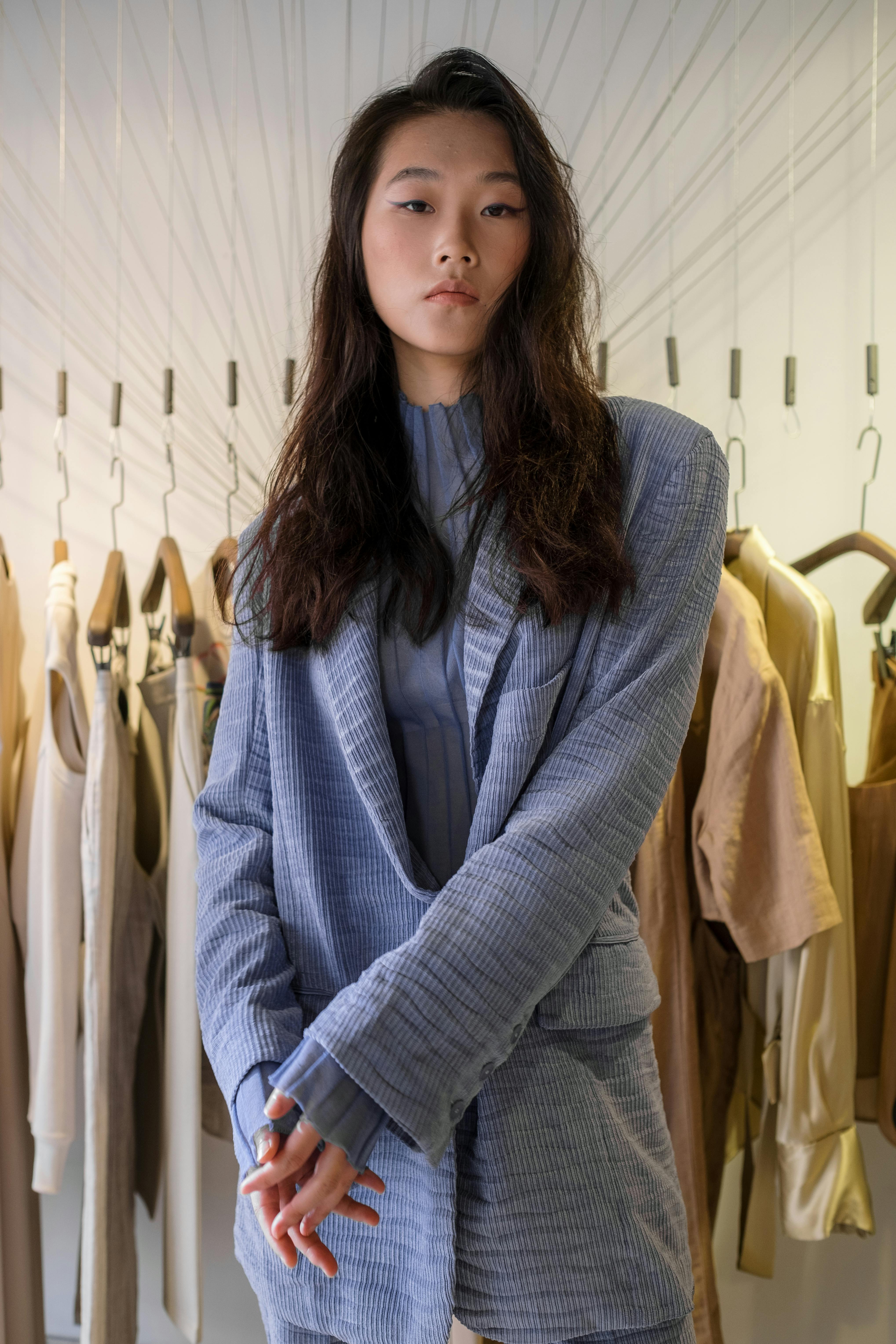 Free Fashionable young Asian woman in a stylish blazer posing in a boutique setting. Stock Photo