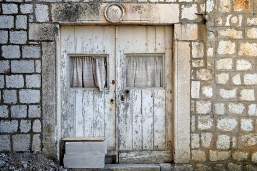 Free Weathered wooden door set in a historic stone wall in Croatia, showcasing rustic charm. Stock Photo