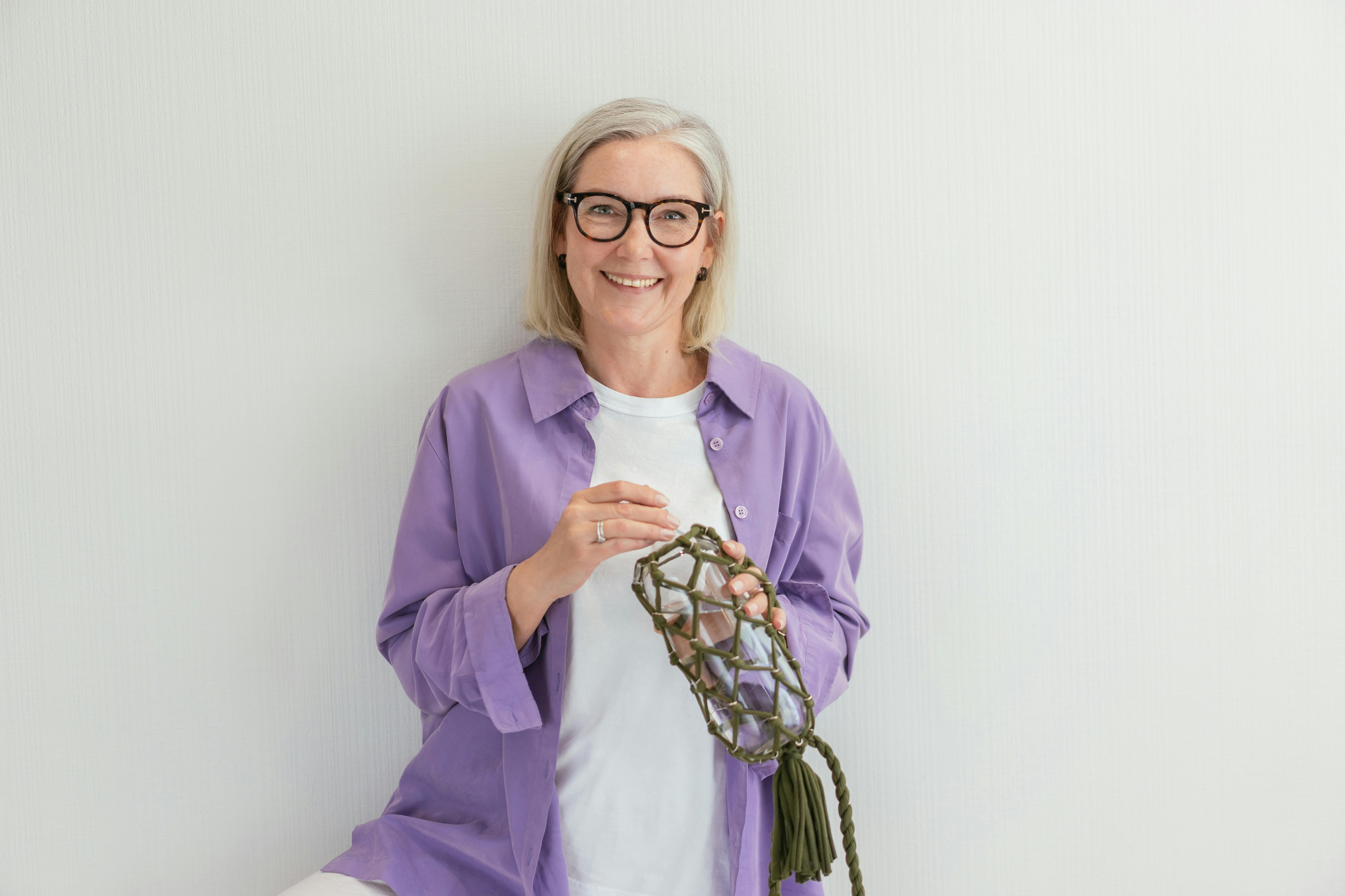 an elderly woman with black framed eyeglasses smiling