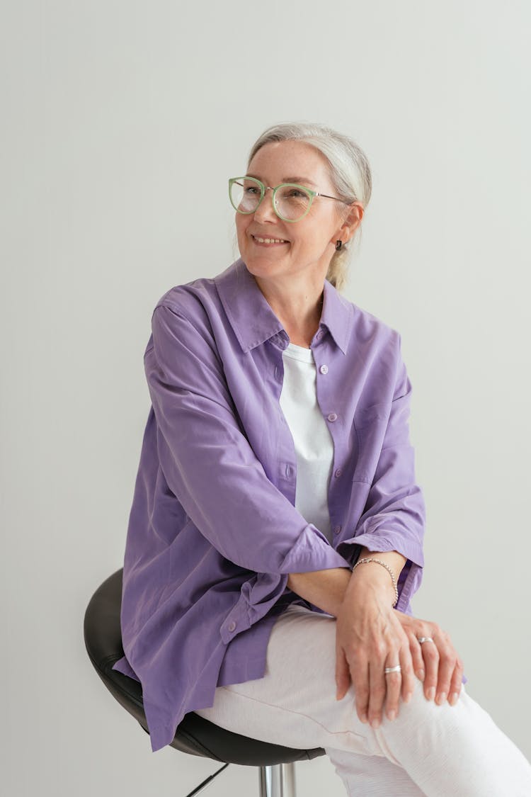 Smiling Woman In Purple Dress Shirt Sitting On Black Chair