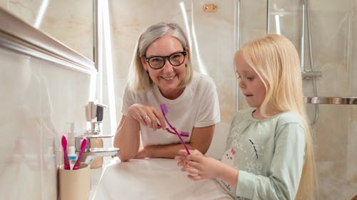 Free A Woman and her Granddaughter Holding Toothbrushes Stock Photo