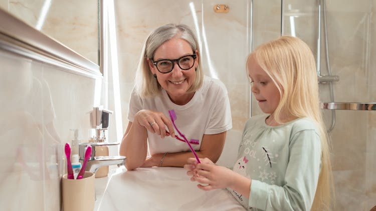 A Woman And Her Granddaughter Holding Toothbrushes