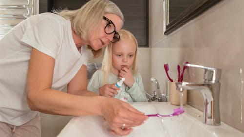 Free Woman Teaching Girl How to Brush her Teeth Stock Photo