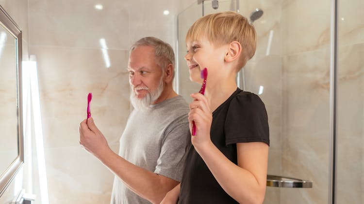 Elderly Man And A Boy Holding Toothbrush