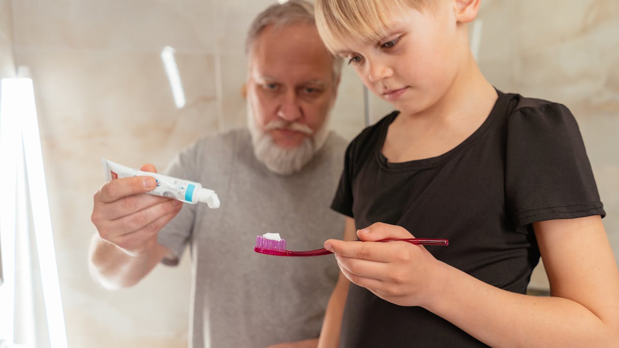 Free A Grandfather Putting Toothpaste on His Granddaughter Toothbrush Stock Photo