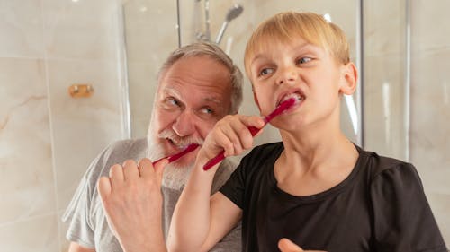 Free Man Brushing his Teeth with his Grandson Stock Photo
