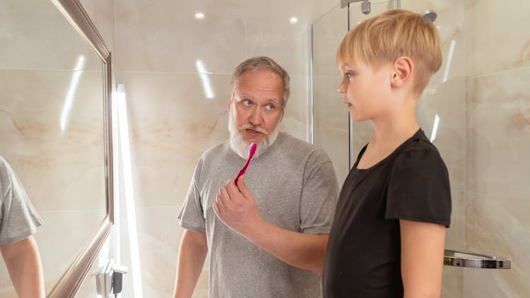 Elderly Man Holding A Toothbrush While Talking To A Boy