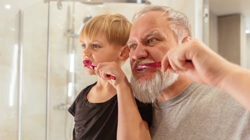 A Man and Young Boy Brushing Teeth Together