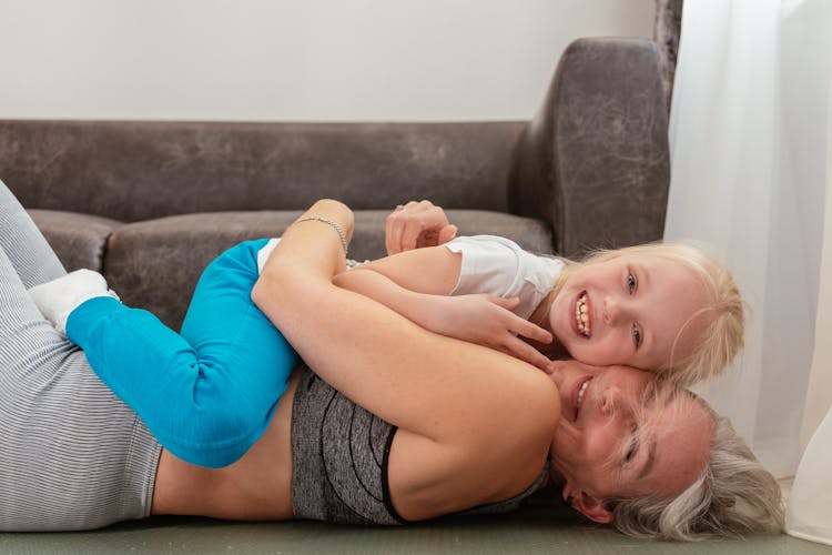 A Grandmother Hugging Her Granddaughter While Lying Down