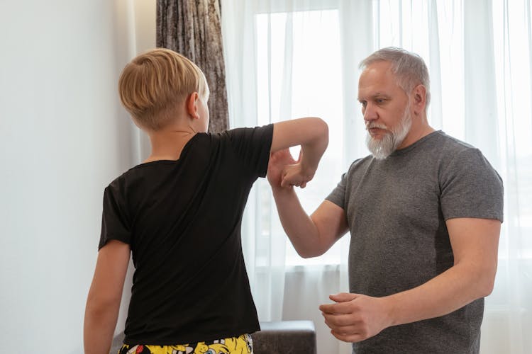 Man In Gray Shirt Teaching A Boy How To Punch