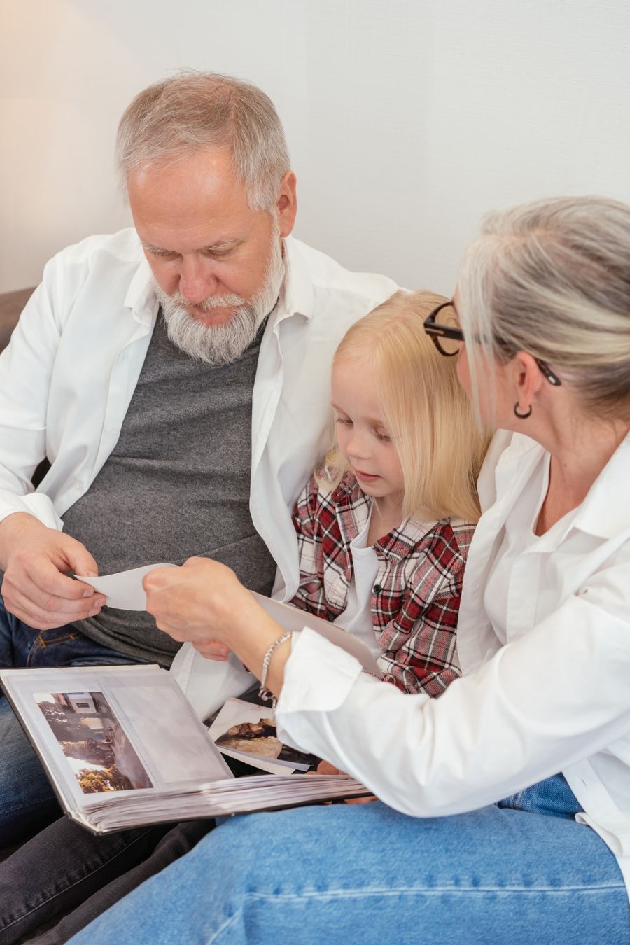 Grandparents looking through a family photo album with their granddaughter at home