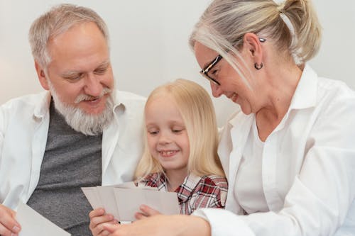 Photo of a Kid and Her Grandparents Looking at Pictures