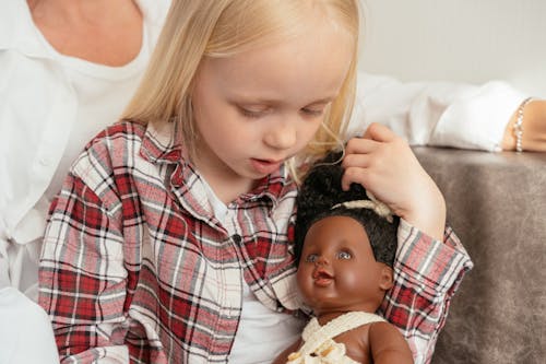 Free Girl in Red and White Plaid Shirt Holding a Doll Stock Photo