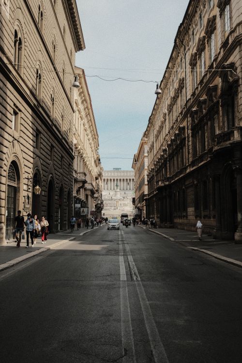 Free Transport driving on asphalt roadway between aged house facades and anonymous people strolling on sidewalks in town Stock Photo