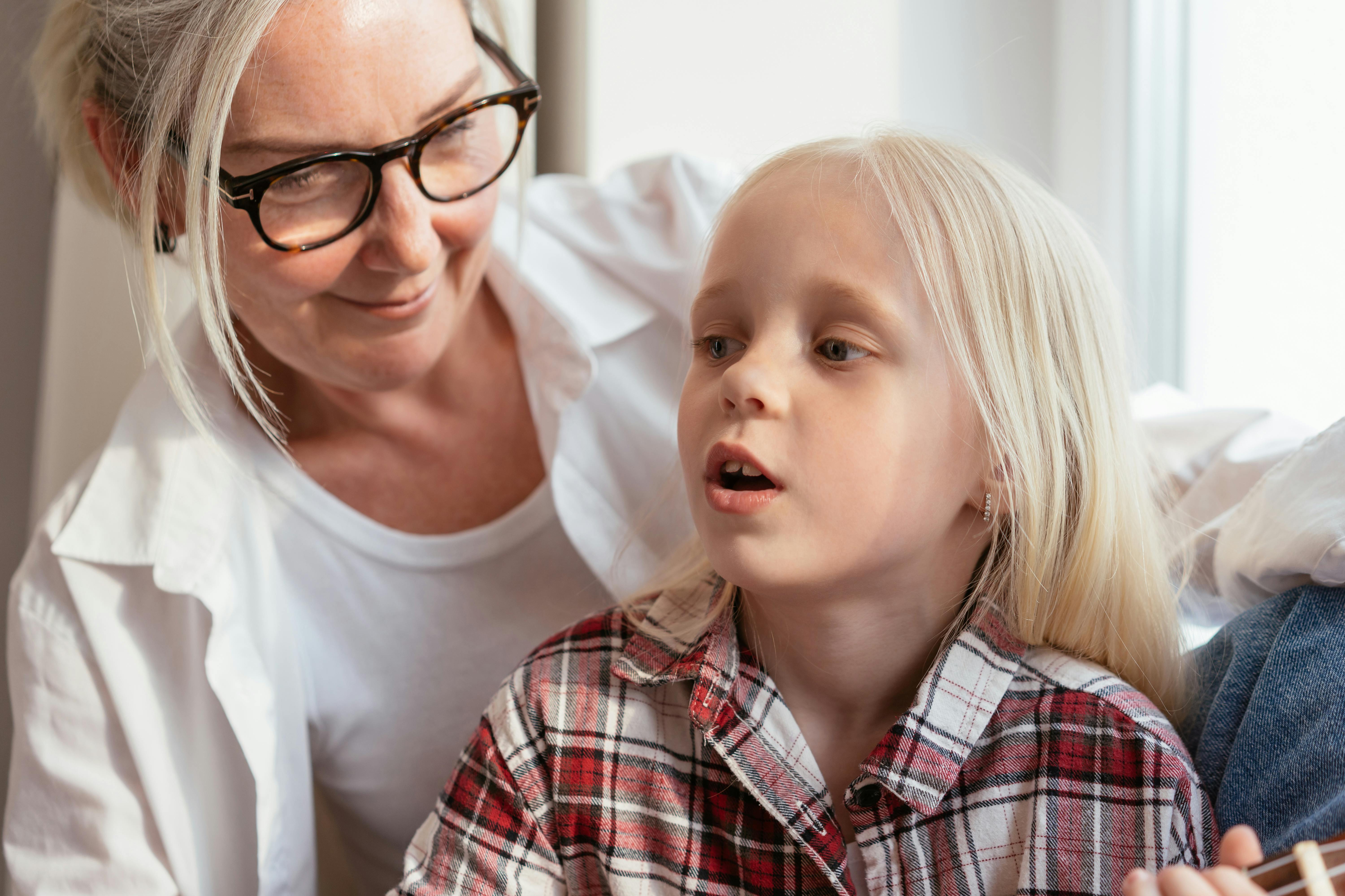 A grandmother and granddaughter enjoying a tender and joyful moment indoors by the window.