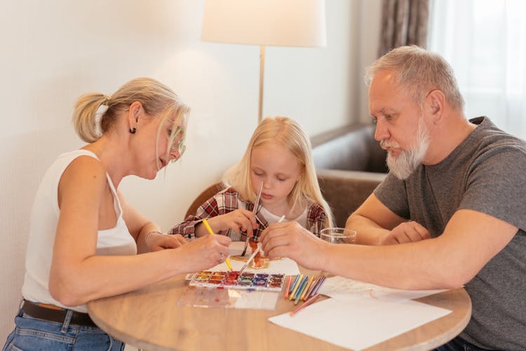 Elderly Grandparents Drawing At Home With Granddaughter