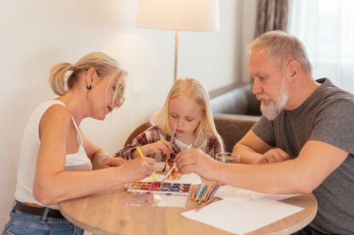 Free A family of three enjoying creative time with painting and drawing at home. Stock Photo