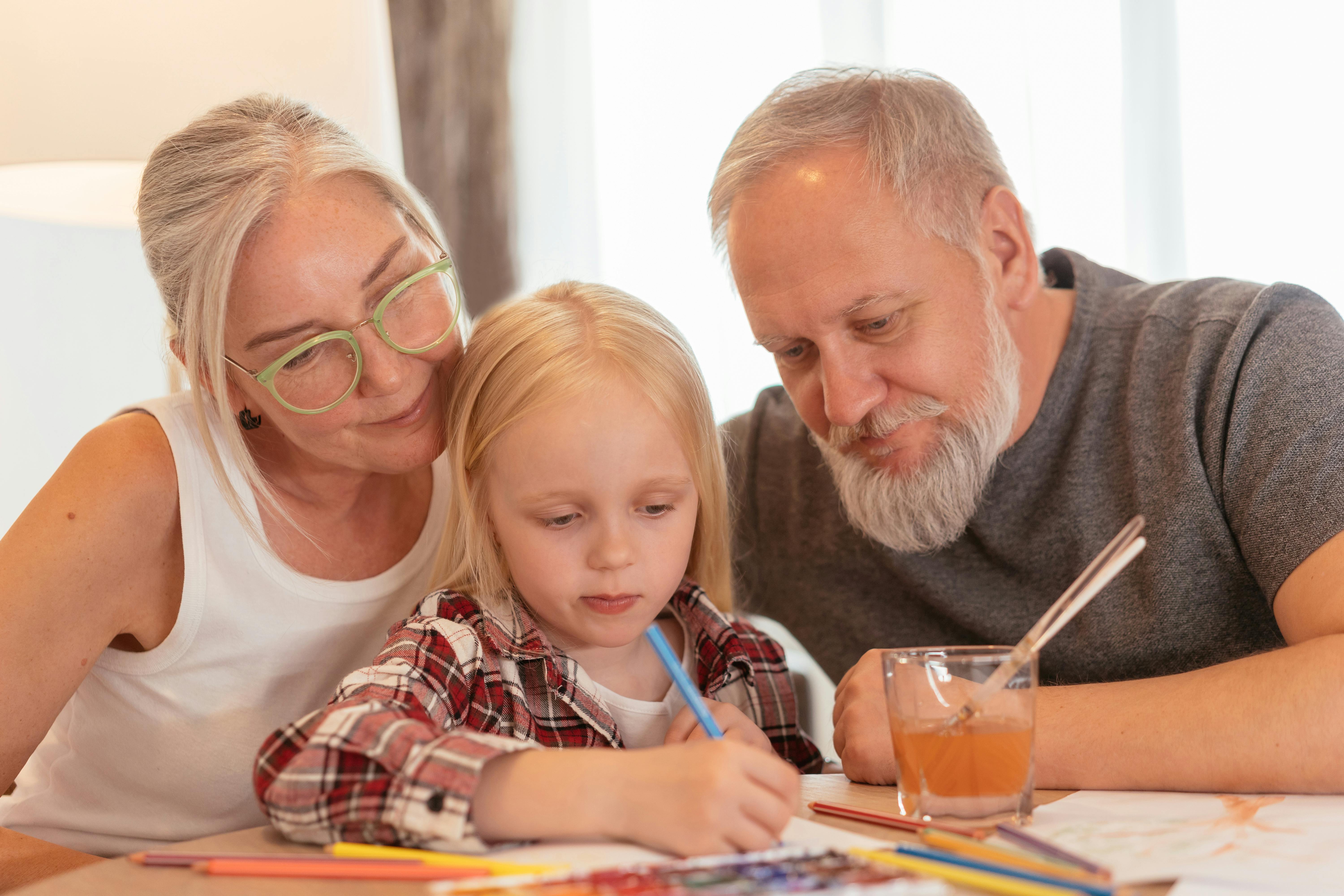 a little girl coloring with her grandparents