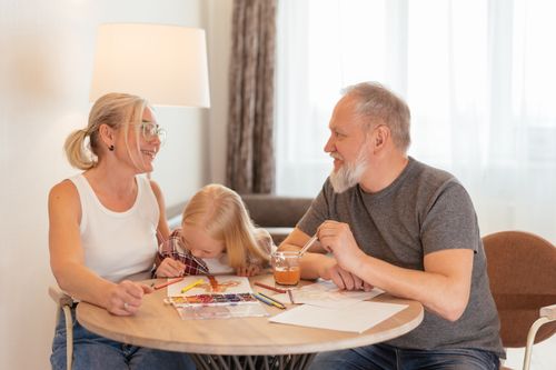 Free Grandparents and a child bond over painting at a cozy home setting, smiling and focused. Stock Photo