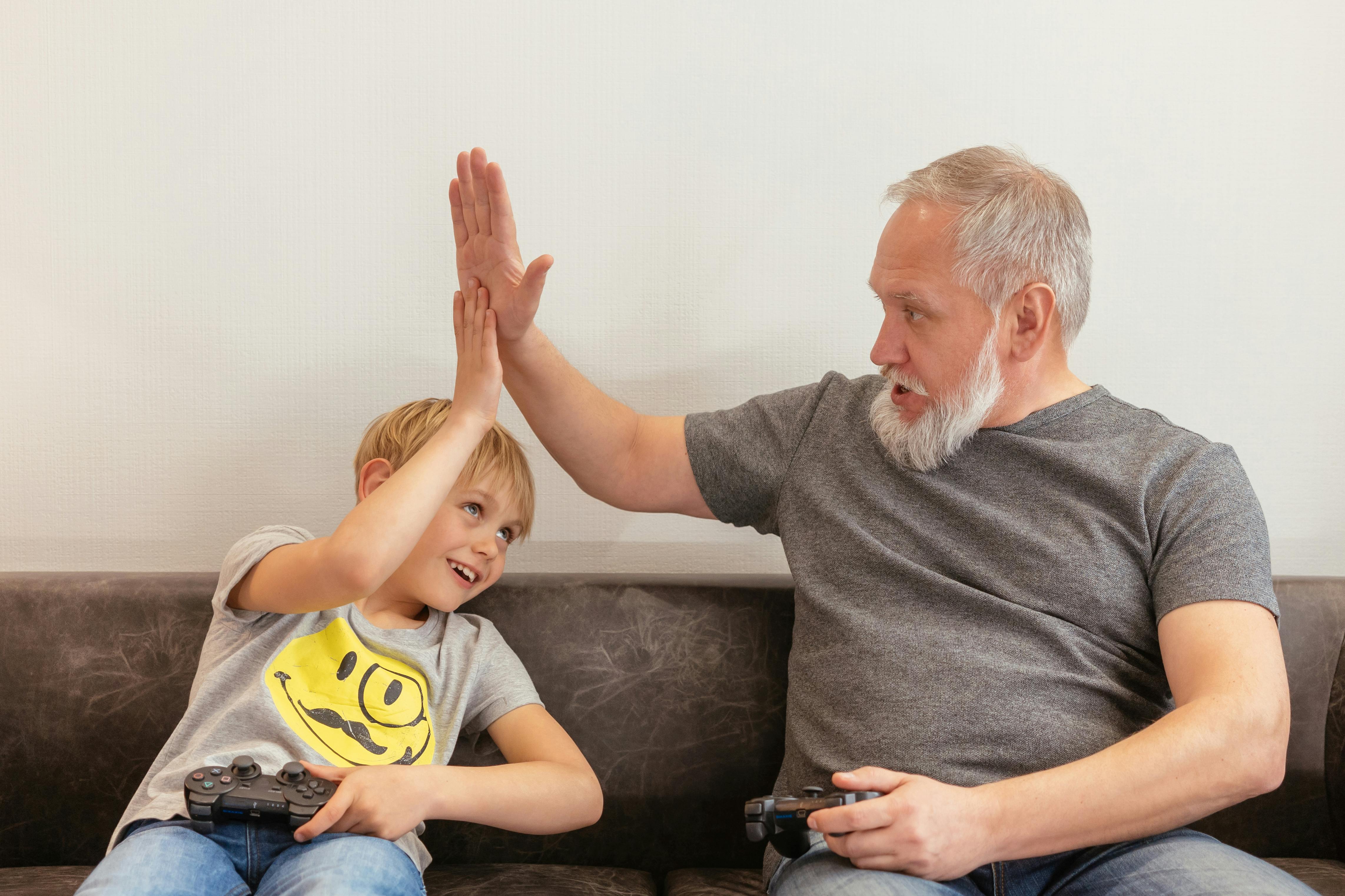a man doing a high five while playing a video game with his grandson