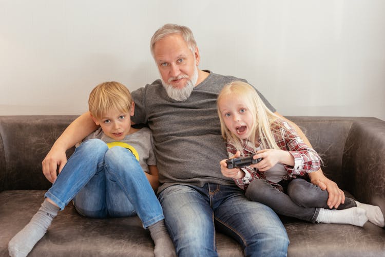 Elderly Man Sitting On Sofa With Kids