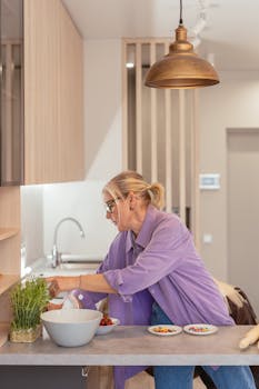 Senior woman in purple shirt preparing food in a stylish kitchen with herbs and candy.