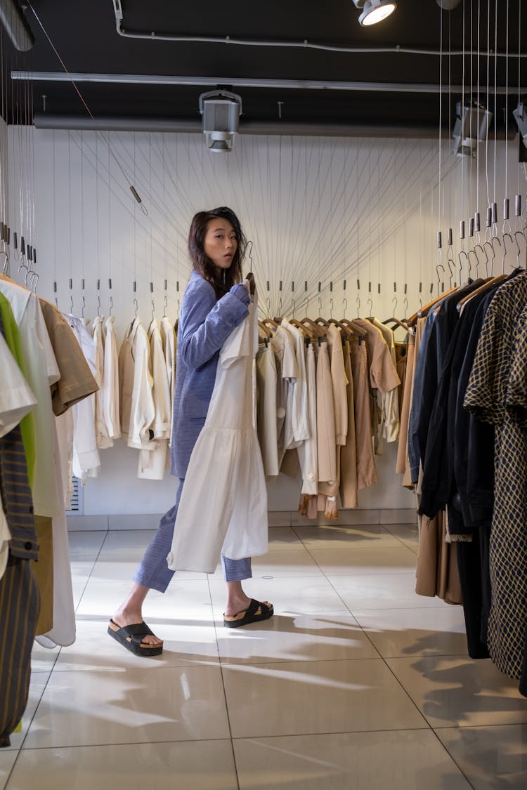 A Woman Holding A Dress At A Clothing Store